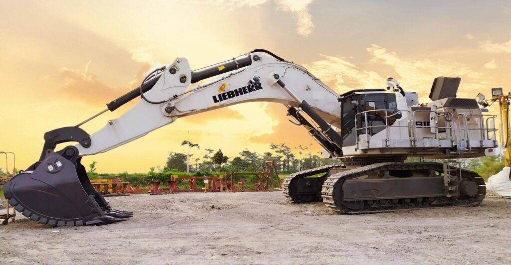 Image of a white Liebherr excavator in front of a sunset