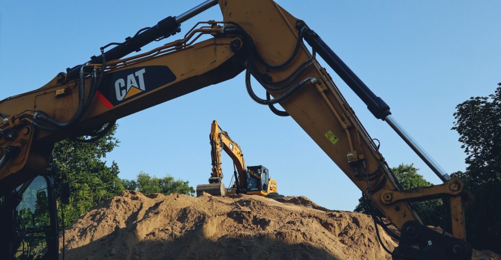 Image of Caterpillar excavators on pile of dirt