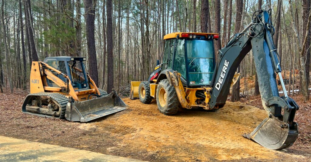 Image of John Deere equipment parked on dirt at the side of the road.