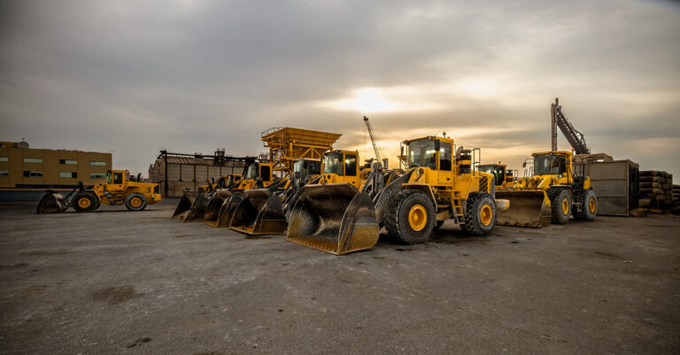 Image of yellow wheel loaders in formation for storage.