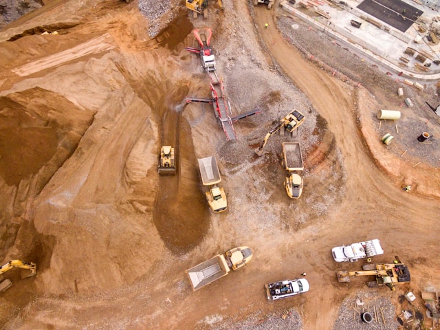 Image looking down on a construction site showing various tractors and dump trucks.