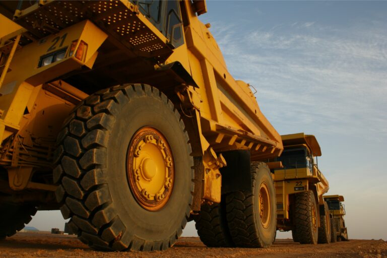 Image of Komatsu mining dump trucks lined up on a dirt road